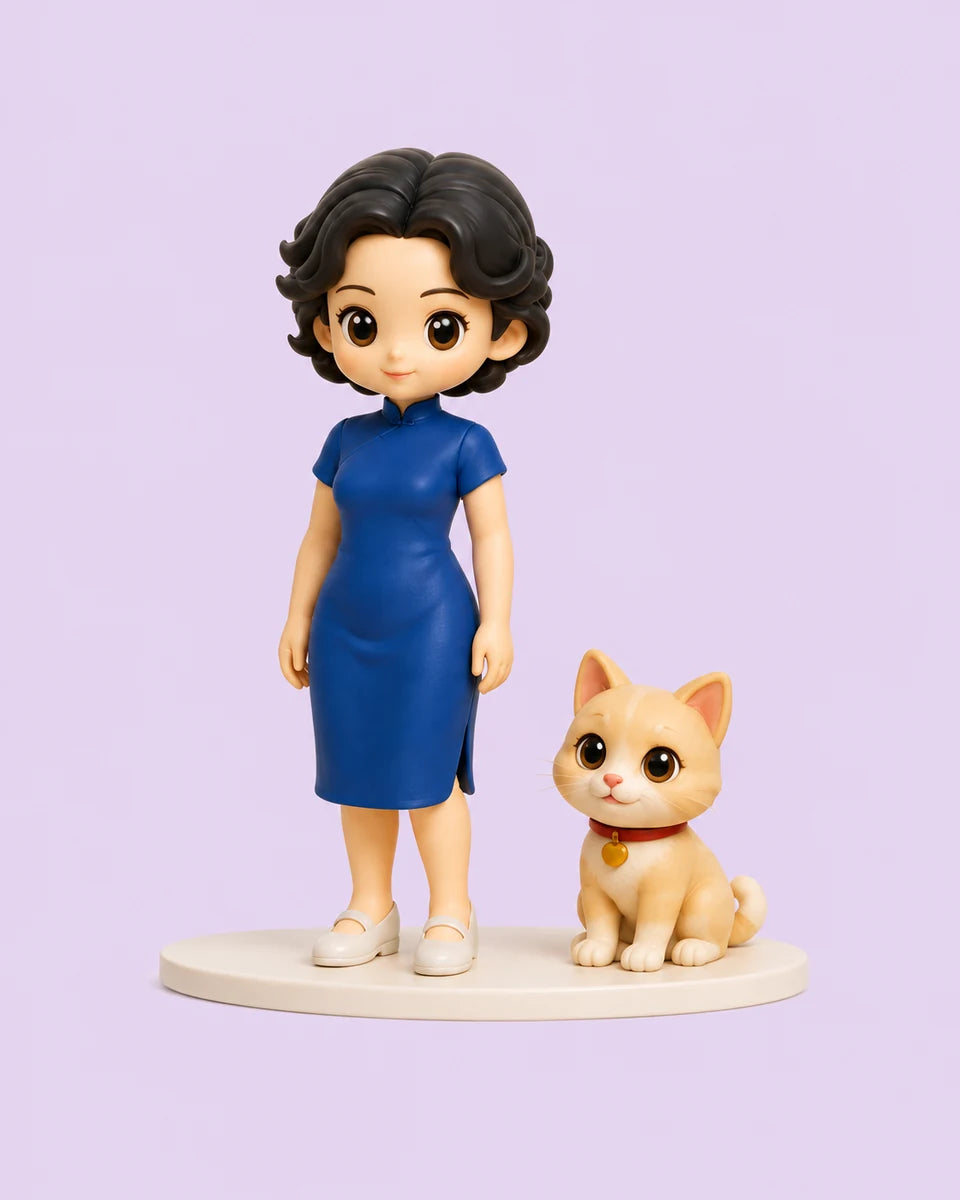 A softly sculpted blue-dress woman and cream ginger cat on an ivory display base